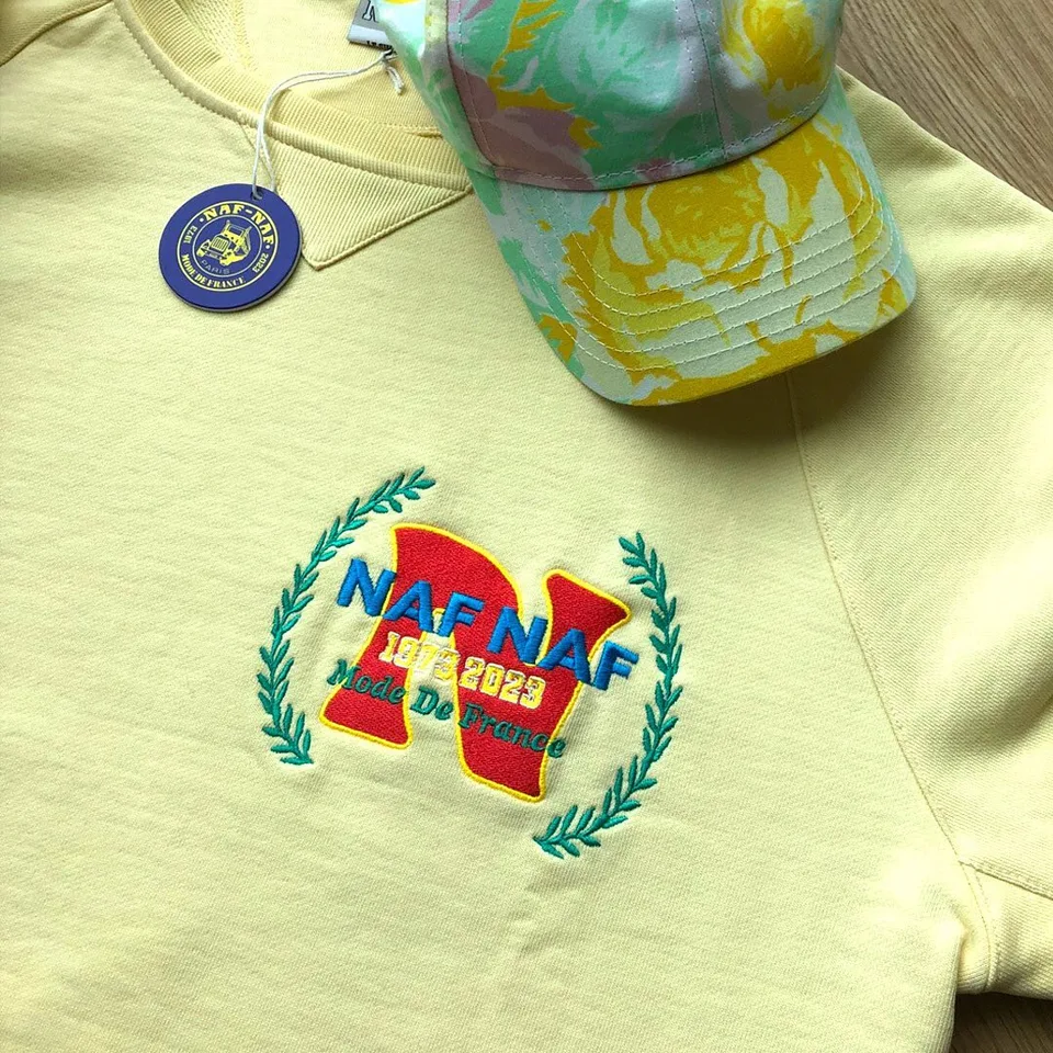 Sweat jaune brodé du logo Naf Naf 1973-2023 et casquette à fleurs