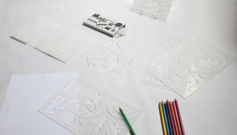 Pochoirs, plaques en relief et crayons de couleur disposés sur une table