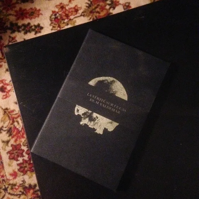 Coffret noir du livre orné d'un crâne argenté, posé sur un tapis
